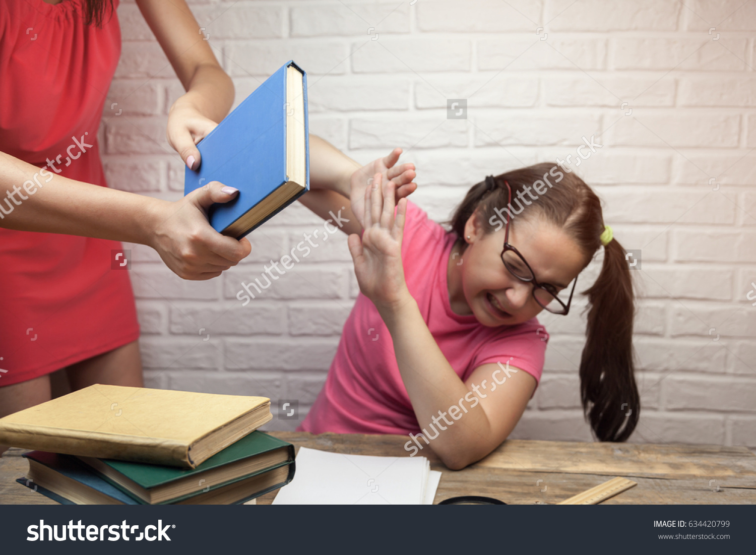 stock-photo-the-mother-beats-her-daughter-with-book-for-lessons-634420799